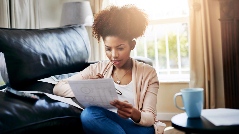 Shot of a young woman going through her paperwork at home.