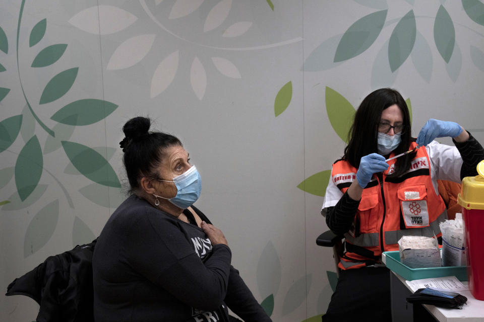 Esther Pamensky, a volunteer with the women's unit of United Hatzalah emergency service, prepares a fourth dose of the COVID-19 vaccine for a woman at Clalit Health Services in Mevaseret Zion, Tuesday, Jan. 11, 2022. (AP Photo/Maya Alleruzzo)