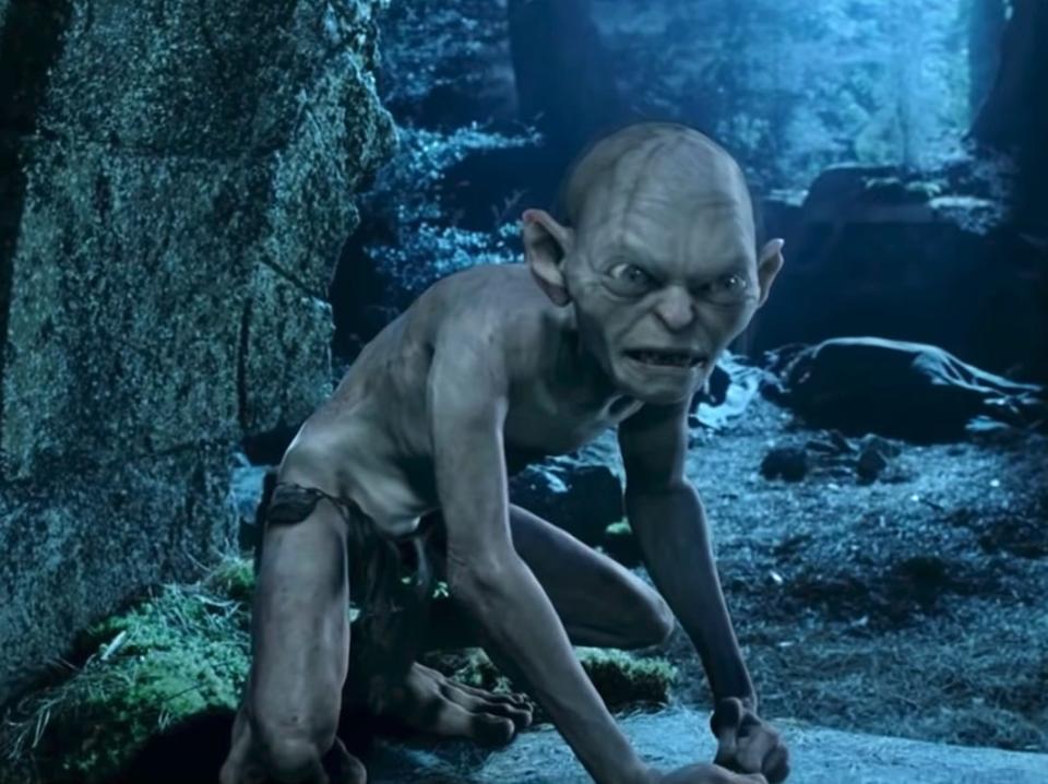 the animated gollum crouching down outdoors in lord of the rings