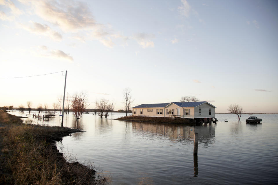 FILE - In this Oct. 22, 2019 photo, a home is surrounded by flood waters in Bartlett, Iowa. Flooding remains a concern in several states along the Missouri River even though the weather has been kind so far this spring. The flood risk remains high in eastern South Dakota, eastern North Dakota, eastern Nebraska, western Iowa, eastern Kansas and Missouri because the soil remains wet, but the lack of rain and warm temperatures this spring allowed snow to melt gradually across the Plains without worsening the risk. (AP Photo/Nati Harnik File)