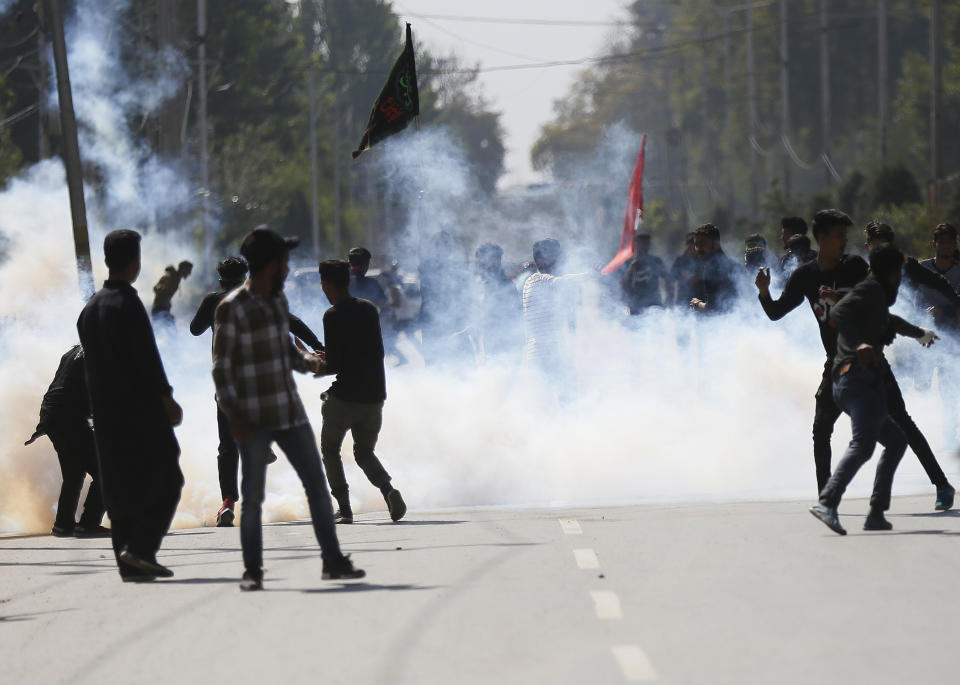 Kashmiri Shiite Muslims shout slogans amid tear smoke as they clash with Indian policemen during a Muharram procession in Srinagar, Indian controlled Kashmir, Wednesday, Sept. 19, 2018. Police and paramilitary soldiers on Wednesday used batons and fired tear gas to disperse hundreds of Muslims participating in religious processions in the Indian portion of Kashmir. Authorities had imposed restrictions in parts of Srinagar, the region's main city, to prevent gatherings marking Muharram from developing into anti-India protests. (AP Photo/Mukhtar Khan)