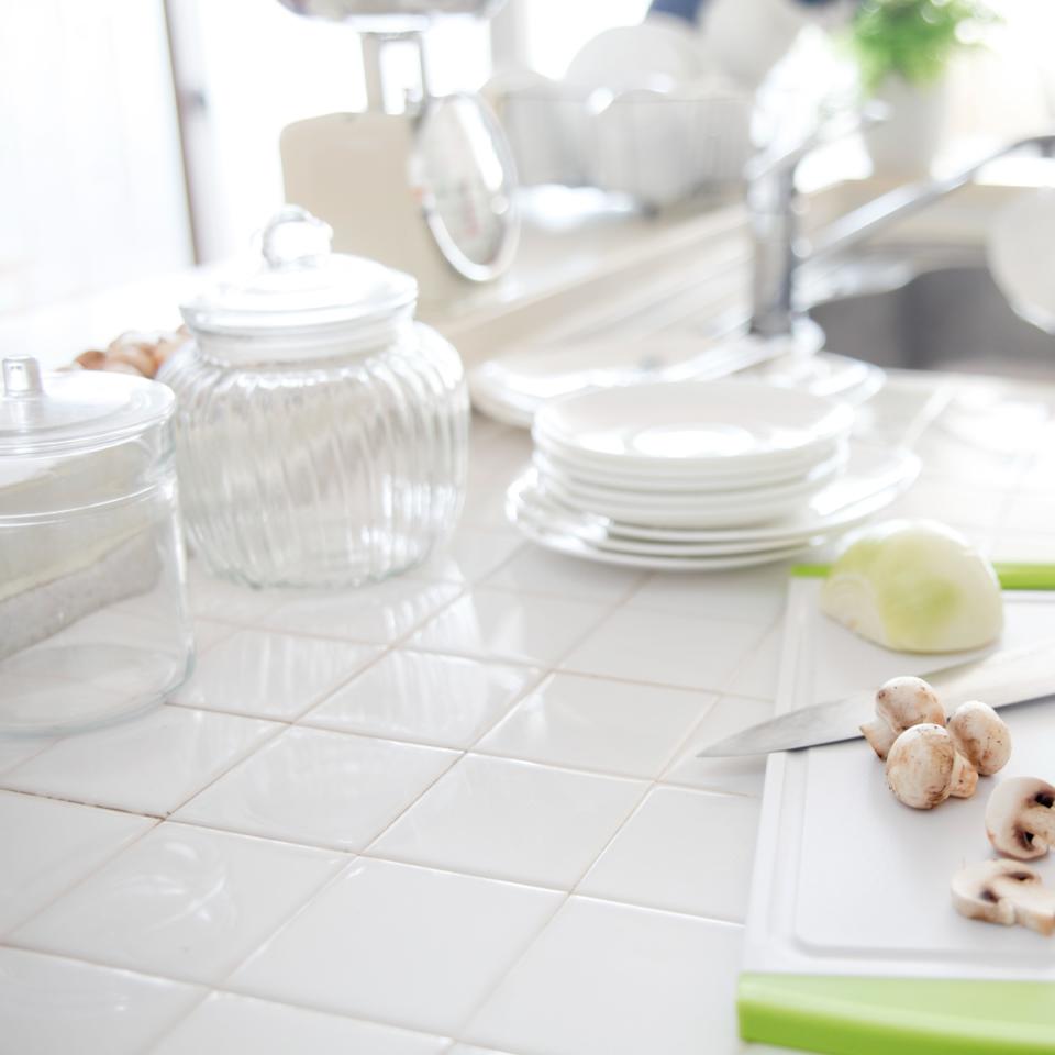 White tiled kitchen countertop with dinnerware and chopping board