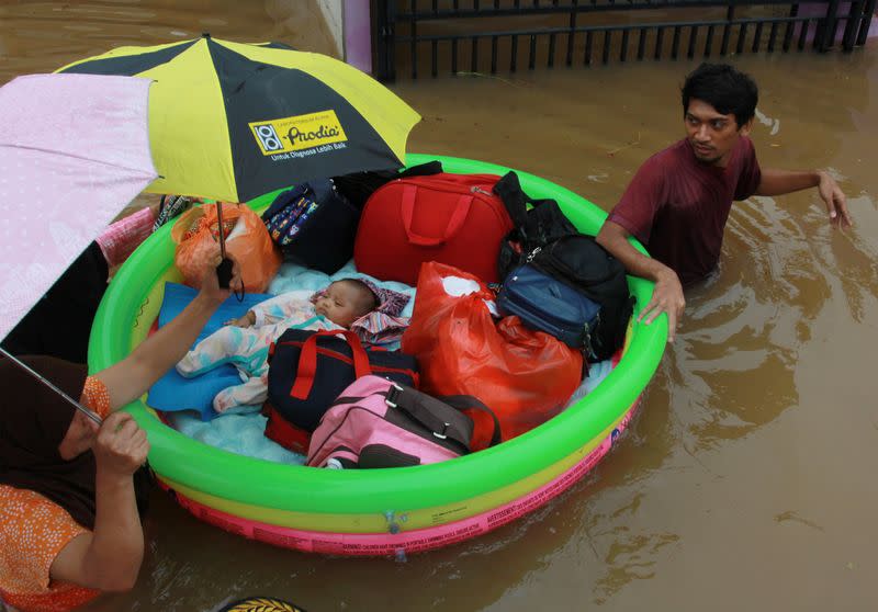 A baby is evacuated by a rescue team using an inflatable boat after floods hit a residential area in Tangerang, near Jakarta, Indonesia