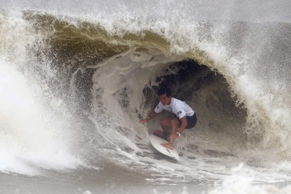 Japan's Hiroto Ohhara is covered by the wave during the quarterfinals of the men's surfing competition at the 2020 Summer Olympics, Tuesday, July 27, 2021, at Tsurigasaki beach in Ichinomiya, Japan. (AP Photo/Francisco Seco)