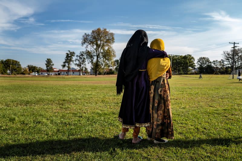 Afghan refugee girls watch a soccer match near where they are staying in the Village at the Fort McCoy, in Wisconsin