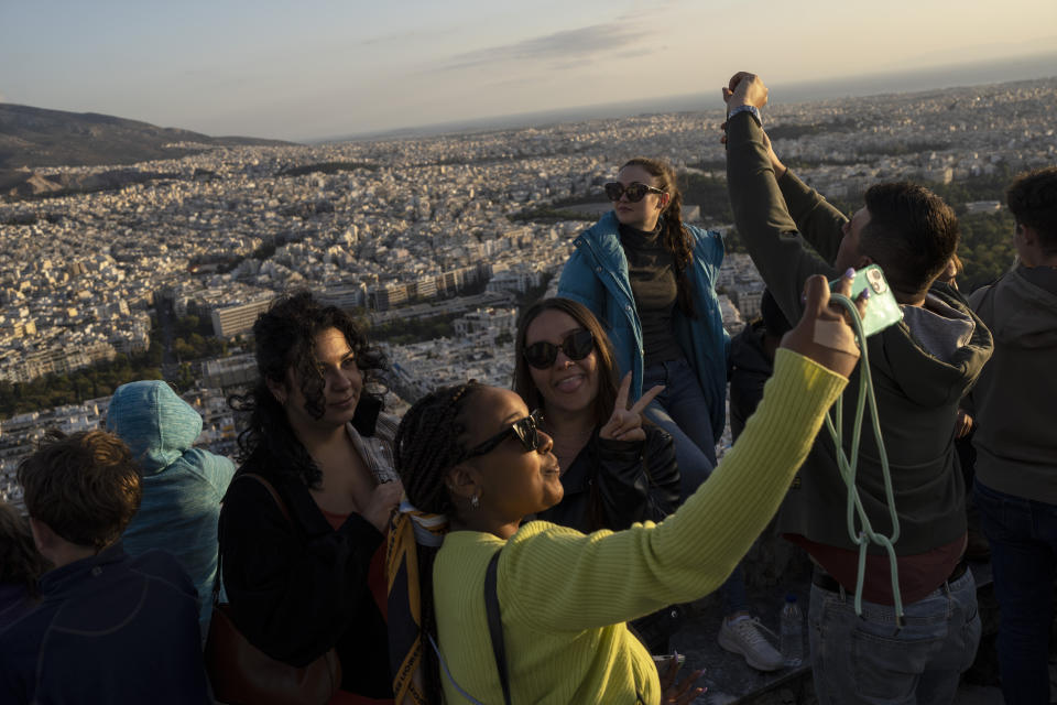 Tourists take pictures at the top of the Lycabettus hill in Athens , on Tuesday, Oct. 18, 2022. The tourism industry in Greece and Portugal are expected to make a full recovery from the pandemic, while other EU members in the Mediterranean have also performed above the expectations of national governments. (AP Photo/Petros Giannakouris)