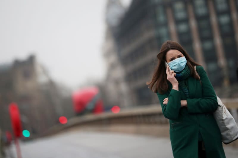 FILE PHOTO: A woman walks across an empty Westminster bridge wearing a protective face mask