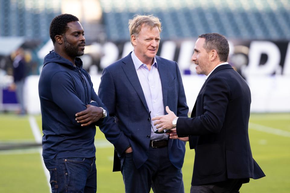 NFL commissioner Roger Goodell talks with former player Michael Vick and Philadelphia Eagles general manager Howie Roseman.
