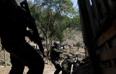 Brazilian Army soldiers fire their weapons during a shootout with drug gangs during an operation in Alemao slums complex in Rio de Janeiro, Brazil August 20, 2018. REUTERS/Ricardo Moraes