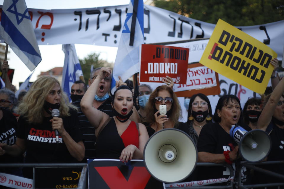 Demonstrators, defying orders to maintain social distancing requirements, chant slogans outside of the Prime Minister's residence in Jerusalem, Tuesday, July 14, 2020. Thousands of Israelis demonstrated outside the official residence of Benjamin Netanyahu, calling on the embattled Israeli leader to resign as he faces a trial on corruption charges and grapples with a deepening coronavirus crisis. The signs read: "You are detached. We are fed up." (AP Photo/Ariel Schalit)