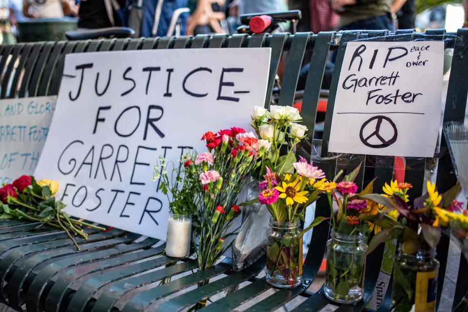 Signs and flowers line a bench at a vigil for Garrett Foster on July 26, 2020 in downtown Austin, Texas.