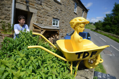 A bust of a cyclist in a yellow wheelbarrow decorates a house on the Tour de France route in Swaledale, northern England, June 18, 2014. REUTERS/Nigel Roddis