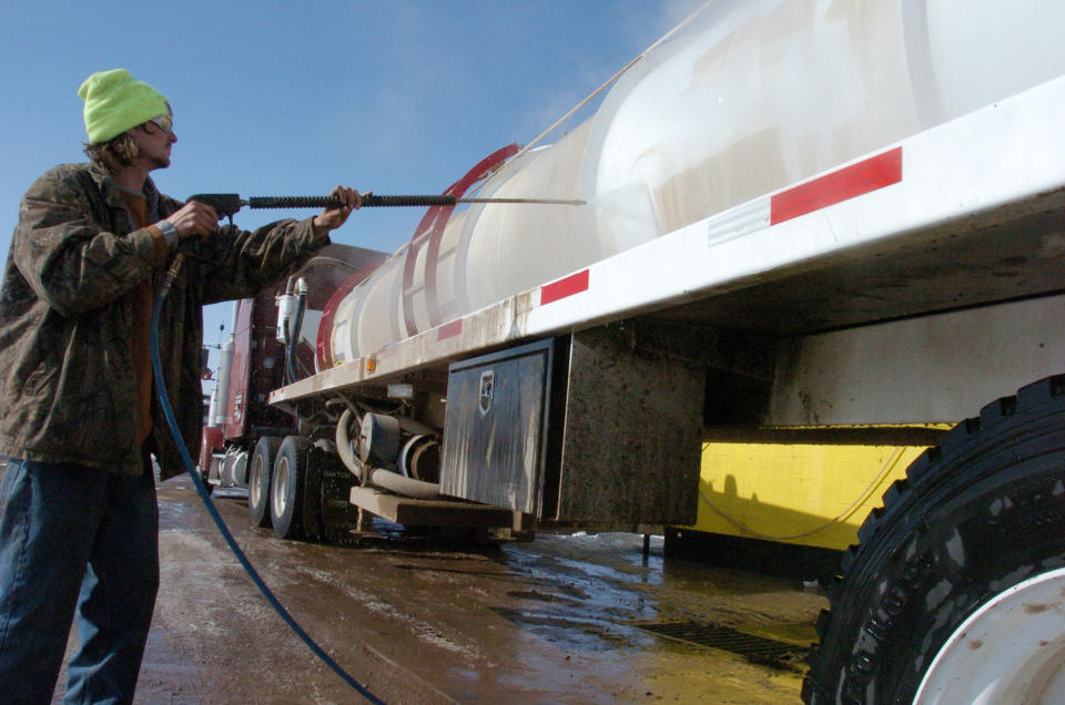 This Feb. 29, 2012 photo shows Kyle Clanton of Shelbyville, Tenn. washing down a water truck used to service the booming Bakken oil fields of eastern Montana and western North Dakota, in Fairview, Mont. More than 16 million barrels of crude are now being pumped every month from the massive Bakken oil field beneath eastern Montana. But Sidney's new-found prosperity doesn't dull the sting of the recent kidnapping and apparent murder of a local teacher, Sherry Arnold, who authorities allege was snatched from a Sidney, Mont., street. (AP Photo/Matthew Brown)