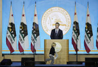 FILE - In this Jan. 7, 2019, file photo, California Governor Gavin Newsom speaks during his inauguration as his son, Dutch, runs around the podium in Sacramento, Calif. Newsom is wrapping up a first year highlighted by the bankruptcy of the country's largest utility, an escalating homelessness crisis and an intensifying feud with the Trump administration, along with record-low unemployment and a booming state economy producing a multi-billion-dollar surplus. (AP Photo/Eric Risberg, File)