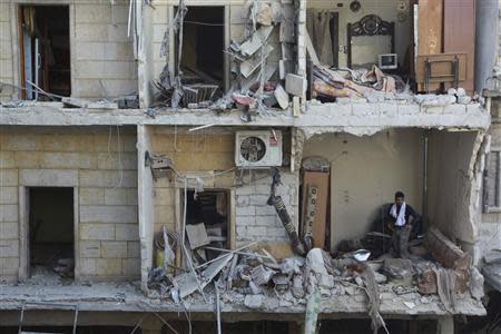 A man stands in a building damaged by what activists said were air strikes from forces loyal to Syria's President Bashar al-Assad in the Maysar neighbourhood of Aleppo December 28, 2013. REUTERS/Jalal Alhalabi