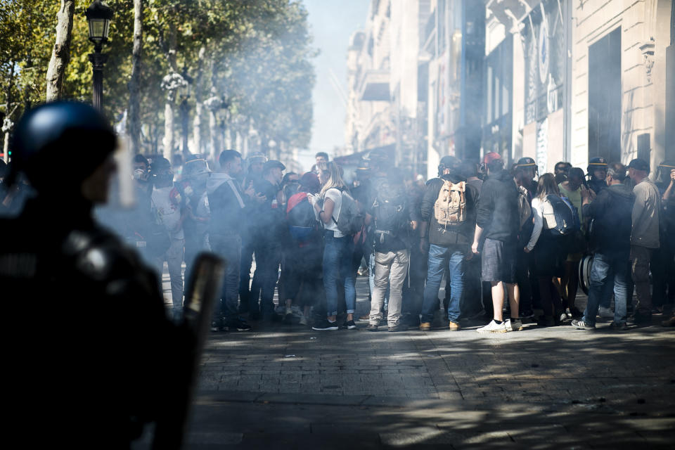 Demonstrators take cover from tear gas fired by riot police officers during a yellow vest demonstration, in Paris, Saturday, Sept 21. 2019. Paris police have used tear gas to disperse anti-government demonstrators who try to revive the yellow vest movement in protest at perceived economic injustice and French President Emmanuel Macron's government. The French capital was placed under high security as few hundred anti-government protesters started marching in the Paris streets. (AP Photo/Kamil Zihnioglu)