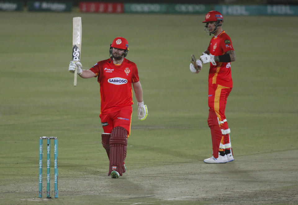 Islamabad United' Paul Stirling, left, raises bat to celebrate after scoring fifty while teammate Alex Hales watches duirng a Pakistan Super League T20 cricket match between Islamabad United and Quetta Gladiators at the National Stadium, in Karachi, Pakistan, Tuesday, March 2, 2021. (AP Photo/Fareed Khan)