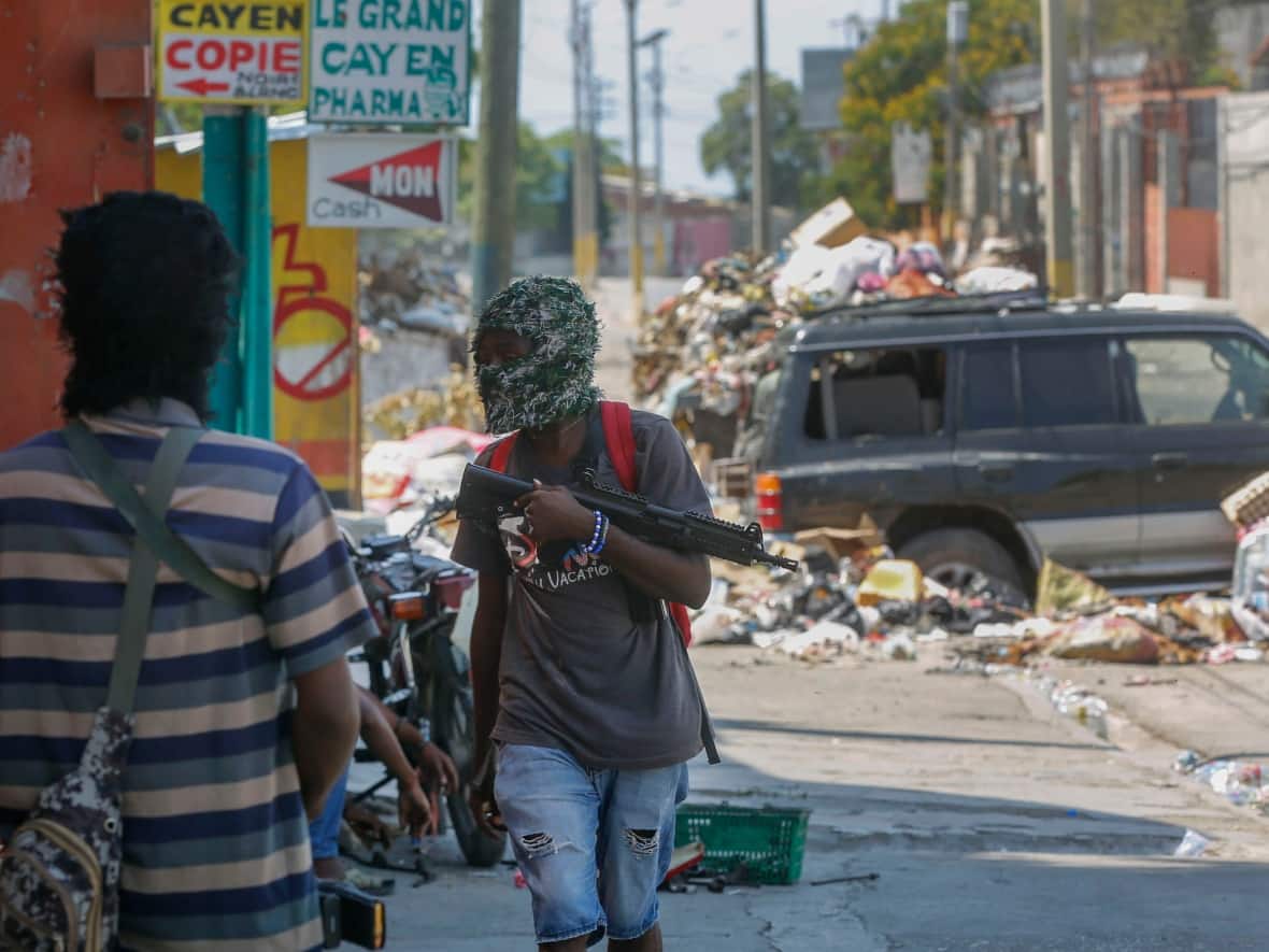 Armed members of the G9 and Family gang stand guard at their roadblock in the Delmas 6 neighbourhood of Port-au-Prince, Haiti's capital, on March 11. (Odelyn Joseph/The Associated Press - image credit)