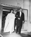 <p>Following a full day of inauguration events, the President and First Lady left the White House for the inaugural ball at the DC Armory. The President is seen in white tie, while Jacqueline Kennedy wears a white cape coat over her evening gown.</p>