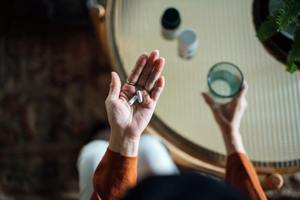 a woman holding pills and a glass of water