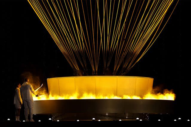 <p>Al Bello/Getty</p> Torchbearers, French Olympians Marie-Jose Perec and Teddy Riner, light the Olympic Cauldron