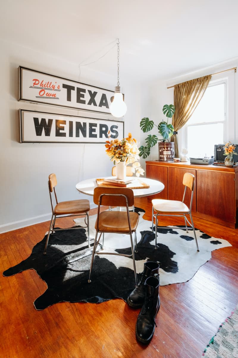 Cowhide rug is laid under tulip table in dining area.