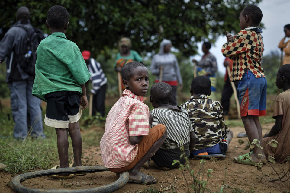 In this photo taken Thursday, April 4, 2019, a boy sits with other children of genocide survivors and perpetrators in the reconciliation village of Mbyo, near Nyamata, in Rwanda. Twenty-five years after the genocide the country has six "reconciliation villages" where convicted perpetrators who have been released from prison after publicly apologizing for their crimes live side by side with genocide survivors who have professed forgiveness. (AP Photo/Ben Curtis)