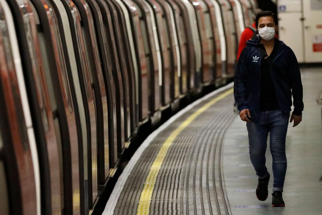 A commuter, wearing PPE (personal protective equipment) as a precautionary measure against COVID-19, walks along the platform at a tube station London on April 22, 2020, as Britain remains under lockdown during the novel coronavirus COVID-19 pandemic. - British Prime Minister Boris Johnson tentatively began his return to work on Tuesday after being hospitalised for coronavirus, as parliament returned and criticism grew over the government's response to the outbreak. (Photo by Tolga AKMEN / AFP) (Photo by TOLGA AKMEN/AFP via Getty Images)