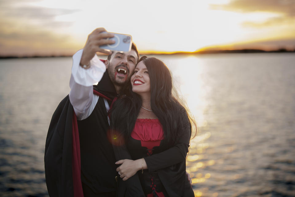 A man wearing a Dracula costume, takes a selfie photograph with his partner at the West Side Hallo Fest, a Halloween festival in Bucharest, Romania, Saturday, Oct. 28, 2023. Tens of thousands streamed last weekend to Bucharest's Angels' Island peninsula for what was the biggest Halloween festival in the Eastern European nation since the fall of Communism. (AP Photo/Vadim Ghirda)