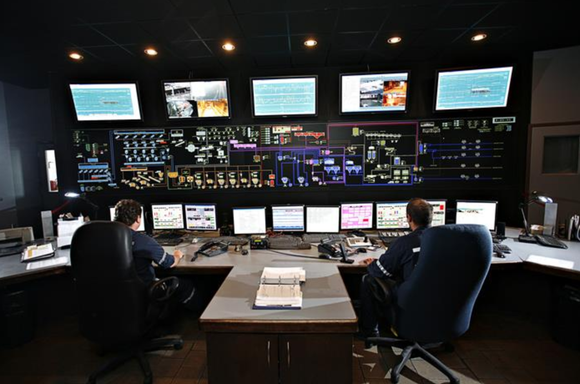 Workers sit behind large computer terminals.