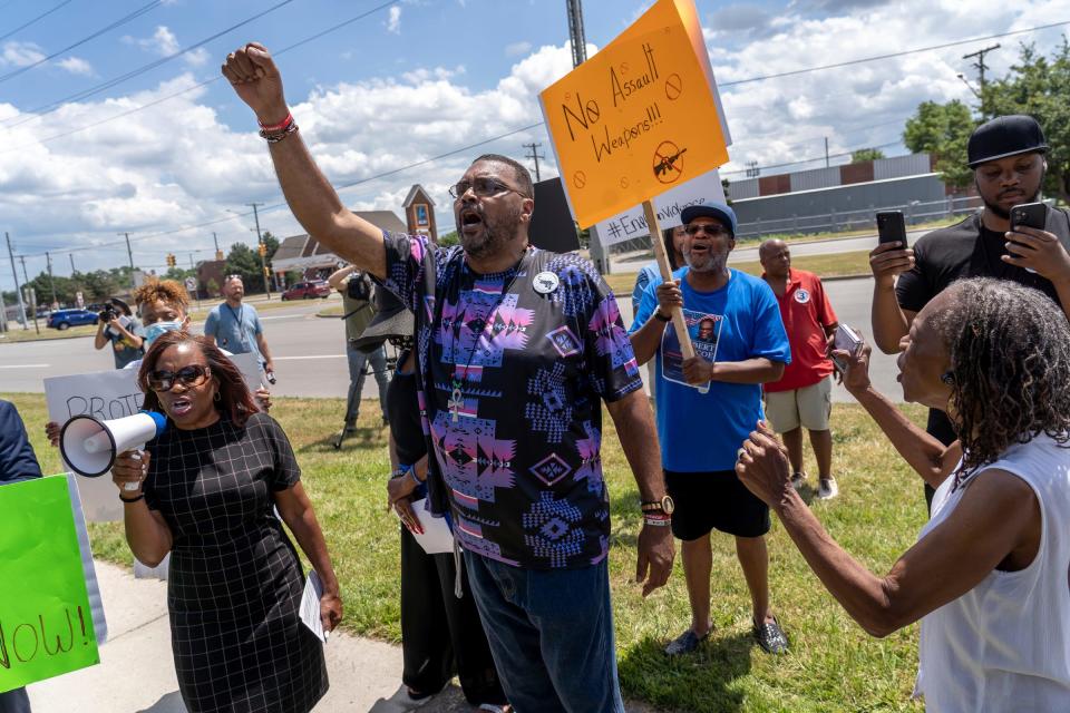 Minister Malik Shabazz, center, of Detroit, holds his hand up while protesting against gun violence with others outside of Action Impact Firearms & Training Center in Eastpointe on July 12, 2022. The gun shop is where the Draco firearm used in the killing of Detroit police officer Loren Courts was purchased.