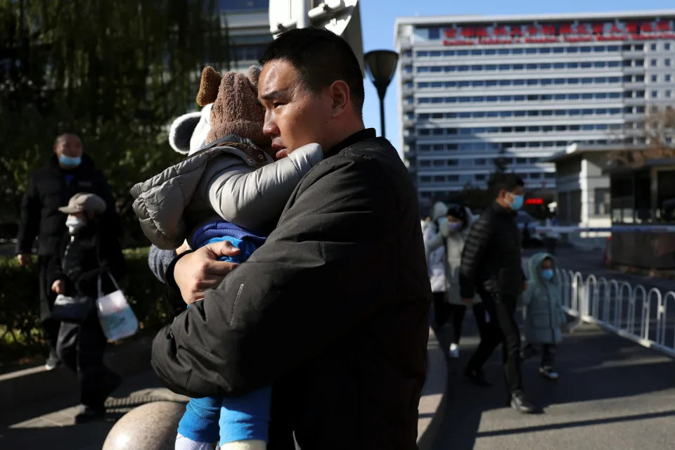中國大陸流感疫情已連續5周快速攀升，是過去3年同期的2.5倍，這波以兒童為主的疫情發現由5種病原體造成。圖為中國大陸北京的家長帶小孩看完診後，在一家兒童醫院外等待乘車。（路透社）