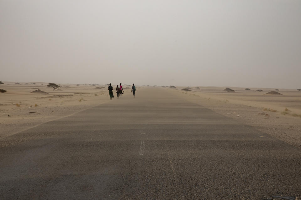 In this July 23, 2019 photo, Ethiopian migrants walk along a road in a sandstorm in Lahj, Yemen. More than 150,000 migrants landed in Yemen in 2018, a 50% increase from the year before, according to the International Organization for Migration. (AP Photo/Nariman El-Mofty)