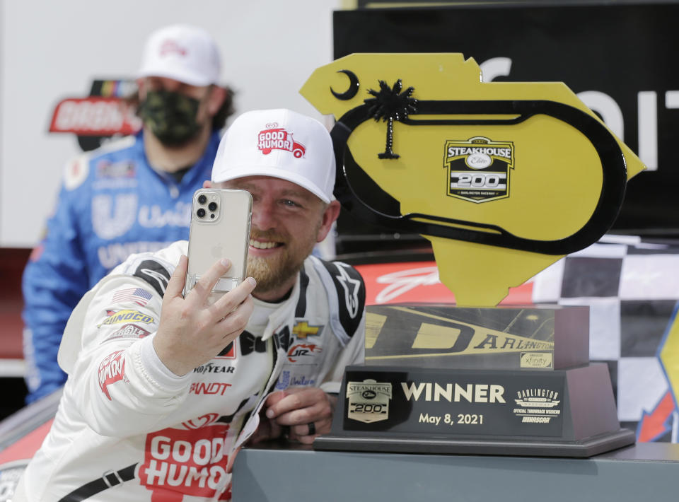 Justin Allgaier takes a photo with his trophy in Victory Lane after winning the NASCAR Xfinity Series auto race at Darlington Raceway, Saturday, May 8, 2021, in Darlington, S.C. (AP Photo/Terry Renna)