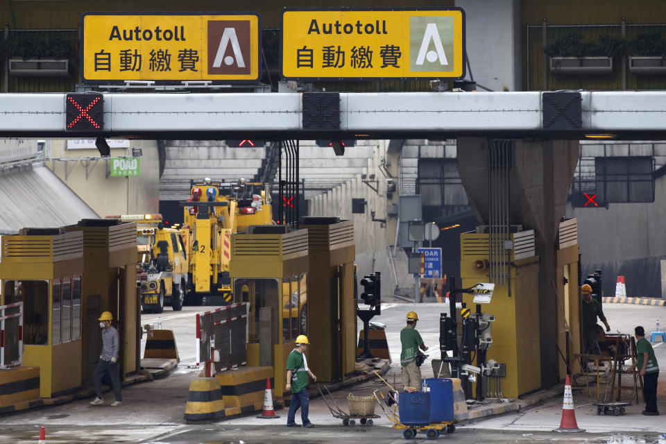 Workers repair tollbooths for the Cross-Harbour Tunnel near the Hong Kong Polytechnic University in Hong Kong, Tuesday, Nov. 26, 2019. A weeklong police siege of a university in Hong Kong may be winding down, closing one of the more violent chapters in the city's long-running anti-government protests. (AP Photo/Ng Han Guan)