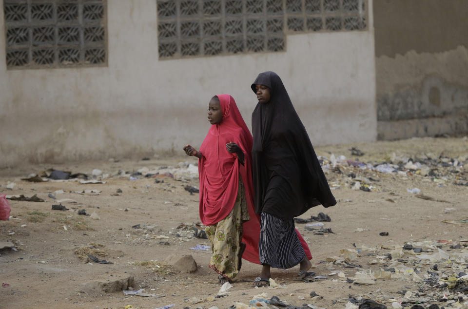 Two young girls walk past a polling station following the presidential election being delayed by the Independent National Electoral Commission in Yola, Nigeria, Saturday, Feb. 16, 2019. A civic group monitoring Nigeria's now-delayed election says the last-minute decision to postpone the vote a week until Feb. 23 "has created needless tension and confusion in the country." (AP Photo/Sunday Alamba)