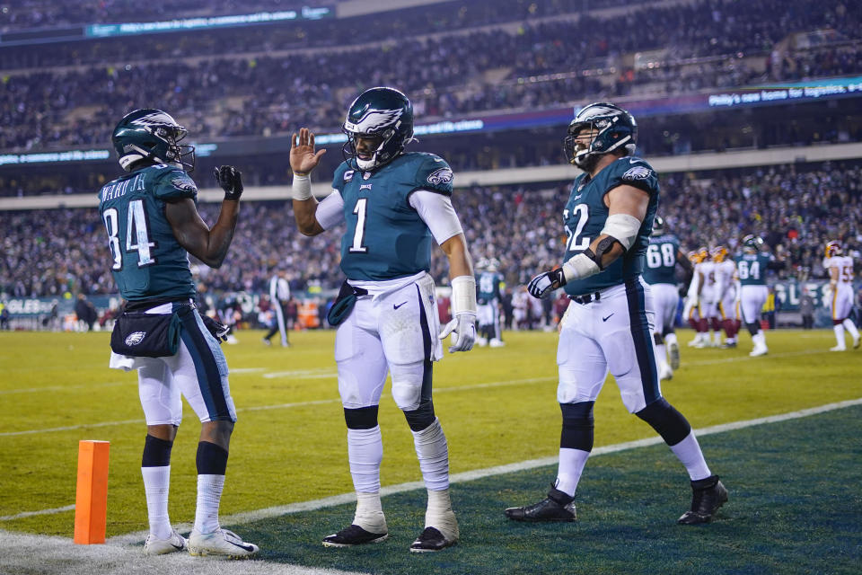 Philadelphia Eagles' Greg Ward, left, celebrates his touchdown with quarterback Jalen Hurts, center, during the second half of an NFL football game against the Washington Football Team, Tuesday, Dec. 21, 2021, in Philadelphia. (AP Photo/Matt Slocum)