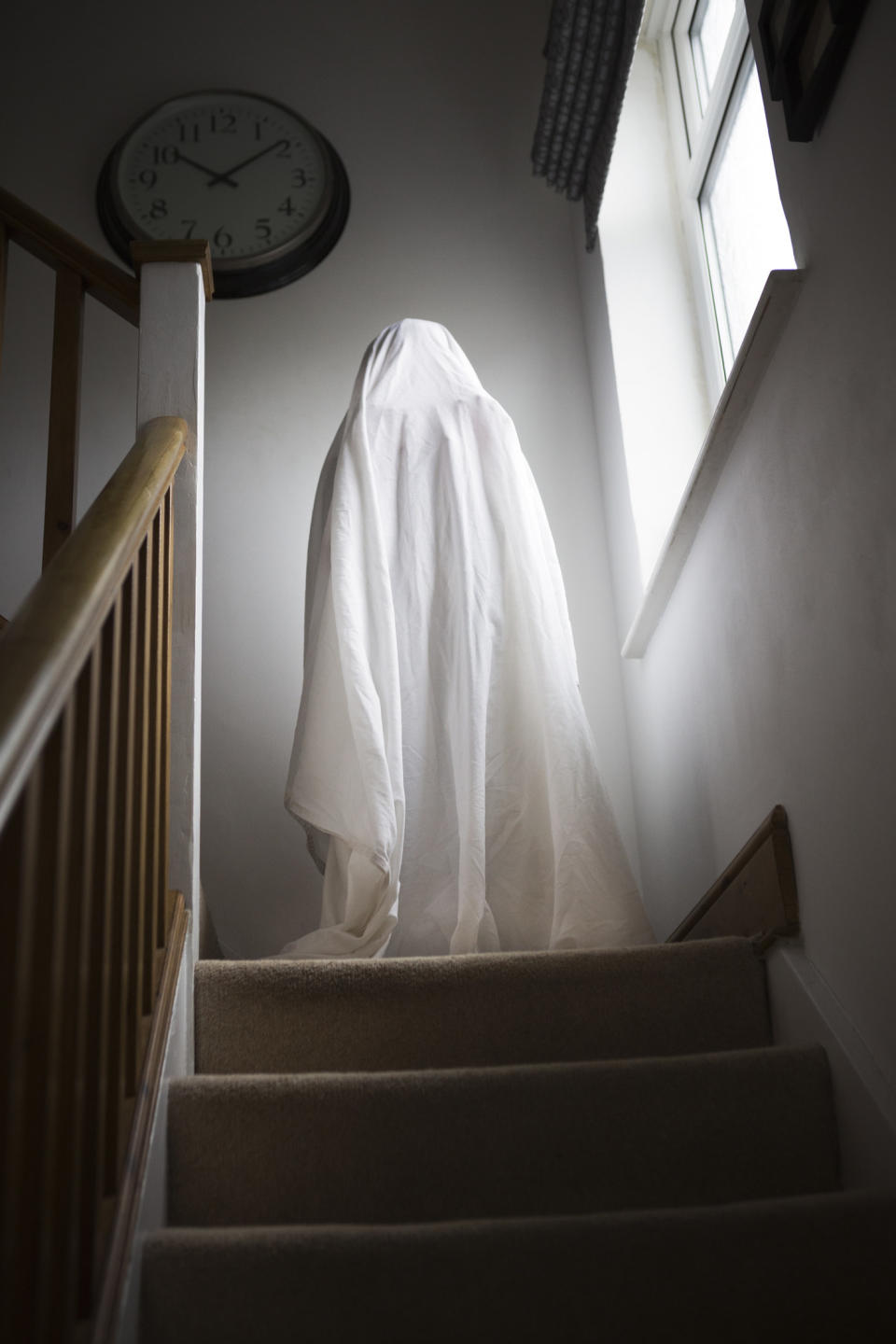 A classic sheet ghost standing at the top of the stairs