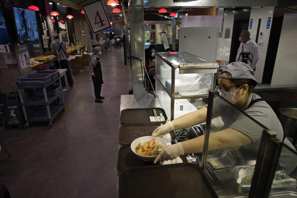 A staff member serves a bowl of noodles over the counter at Dignity Kitchen in Hong Kong on Nov. 17, 2020. Located smack in the middle of Hong Kong's bustling Mong Kok neighborhood, Dignity Kitchen offers an array of mouthwatering Singaporean fare. But what sets Dignity Kitchen apart from other restaurants in the city is that it is a social enterprise, almost entirely staffed by employees with physical or mental disabilities. (AP Photo/Vincent Yu)