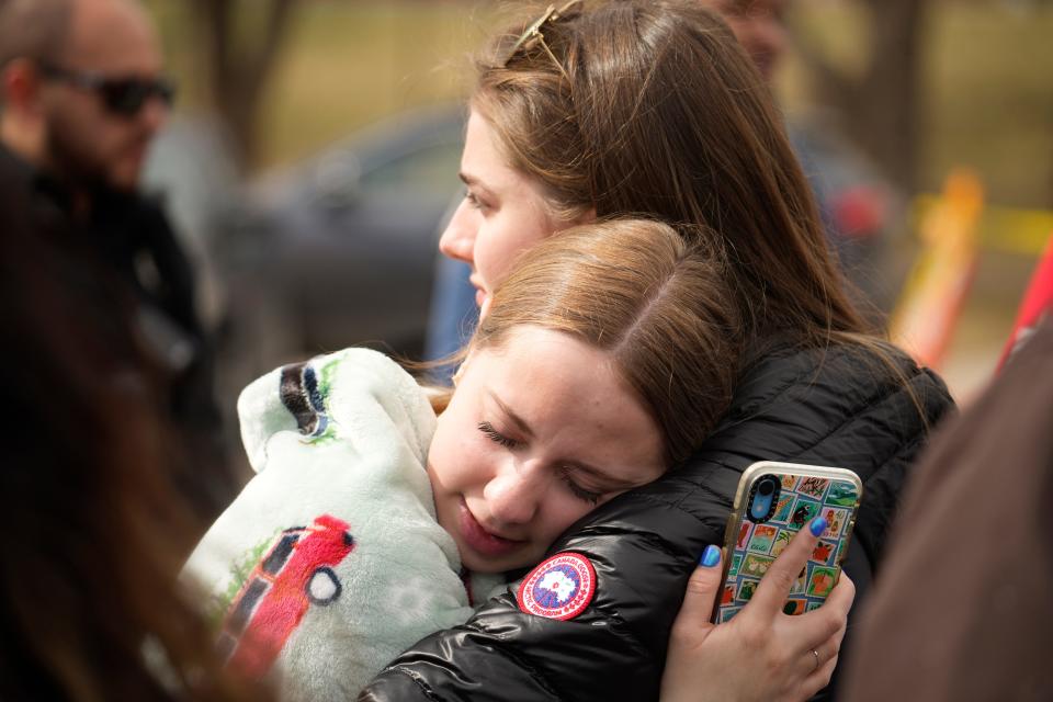 Two women hug after a school shooting at East High School Wednesday, March 22, 2023, in Denver. Two school administrators were shot at the high school Wednesday morning after a handgun was found on a student subjected to daily searches, authorities said.