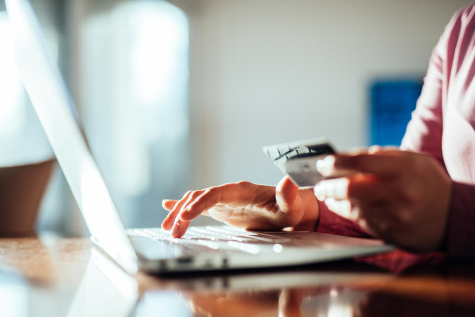 a person holding a credit card and typing into their laptop