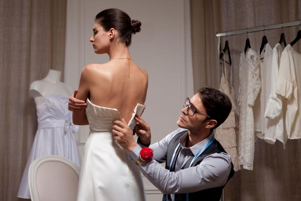 <p>Getty</p> Stock image of a tailor fitting a wedding dress on a bride.