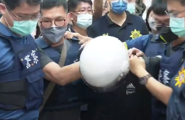 台南殺警案嫌犯林信吾（戴白色安全帽者）落網後，於23日上午被押解進警局。