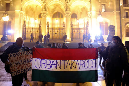 Demonstrators hold a Hungarian flag with the message "Orban go away" during a protest against a proposed new labor law, billed as the "slave law", in front of the parliament building in Budapest, Hungary December 21, 2018. REUTERS/Marko Djurica