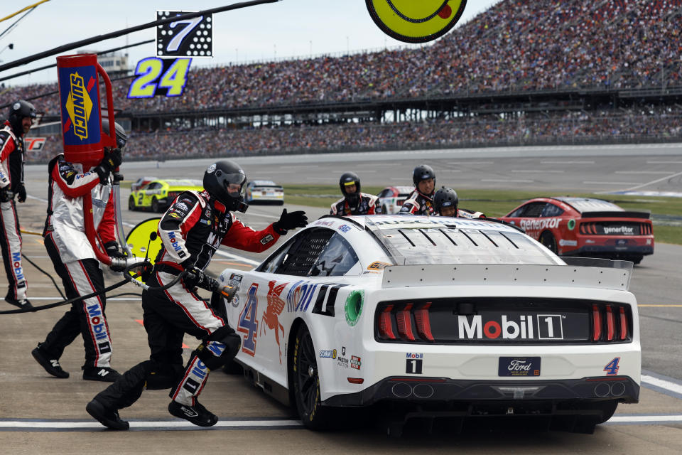 Crew members run to the car of Kevin Harvick for a tire change during a NASCAR Cup Series auto race at Talladega Superspeedway, Sunday, April 23, 2023, in Talladega, Ala. (AP Photo/Butch Dill)