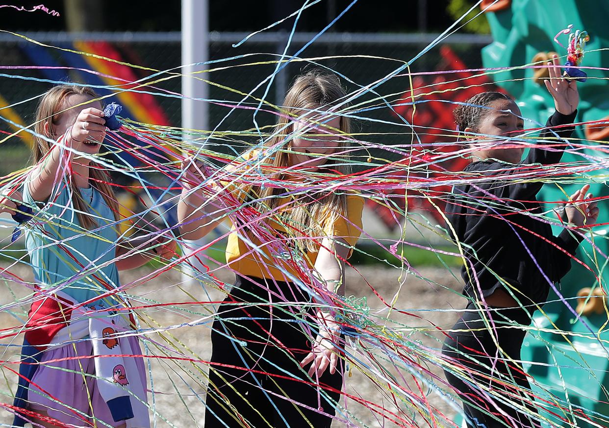 Lucy Adams, left, Coenen and Zari Thompson, right, pop streamers during the inclusive playground ribbon cutting ceremony at Highlands Odyssey Elementary School on Monday, May 6, 2024 in Appleton, Wis. 
Wm. Glasheen USA TODAY NETWORK-Wisconsin