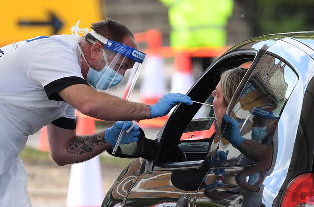 A medical worker takes a swab at a drive-in coronavirus testing facility at the Chessington World of Adventures resort in south west London