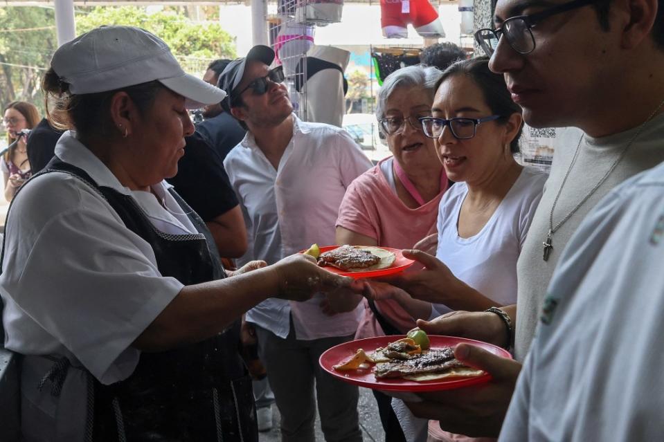 The other half of the shop is packed with standing customers clutching plastic plates and ladling salsa, and the female assistant who rolls out the rounds of tortilla dough constantly. AFP via Getty Images