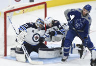 Winnipeg Jets goaltender Connor Hellebuyck (37) makes a pad save next to Toronto Maple Leafs center John Tavares (91) and Jets defenseman Josh Morrissey (44) during the third period of an NHL hockey game Tuesday, March 9, 2021, in Toronto. (Nathan Denette/The Canadian Press via AP)