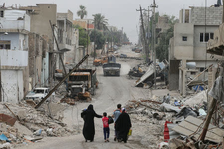 A displaced Iraqi family walks along a street as the battle between the Iraqi Counter Terrorism Service and Islamic State militants continues nearby, in western Mosul, Iraq, April 23, 2017. REUTERS/Marko Djurica